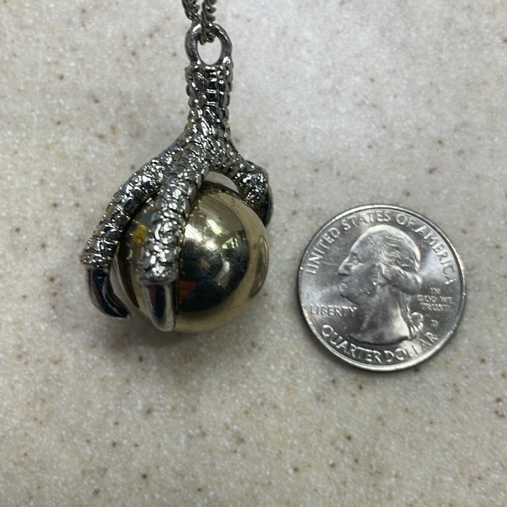 Metal dragon claw holding gold orb necklace.